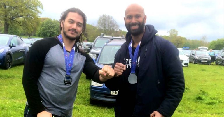 two men wearing wolf run medals and fist bump